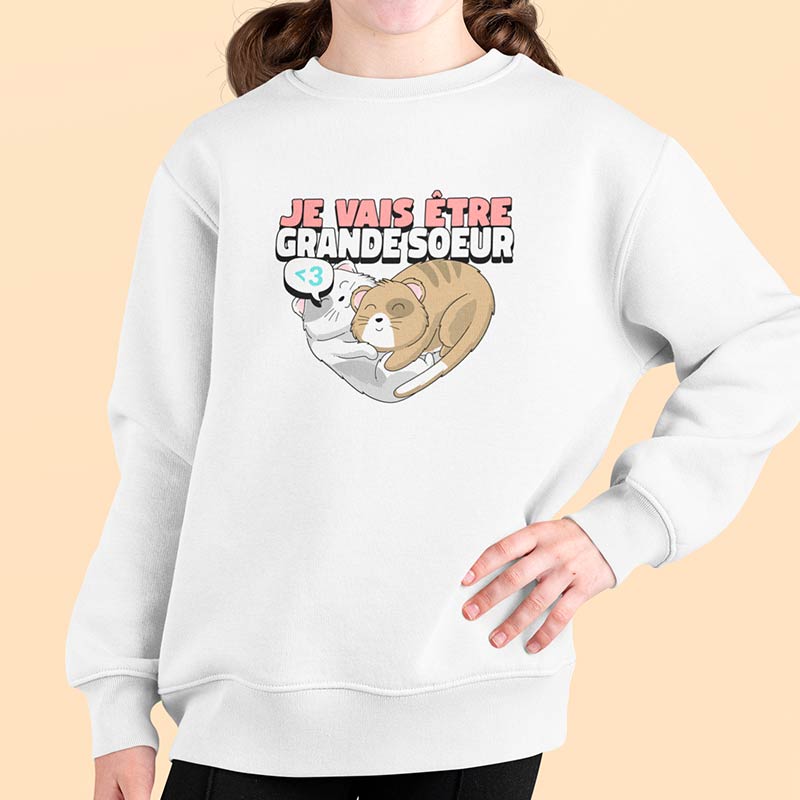 jeune fille avec un pull blanc avec des chats en forme de coeur je vais être grande soeur